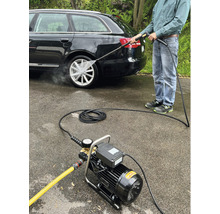 Ein Mann reinigt mit einem Hochdruckreiniger ein Auto.