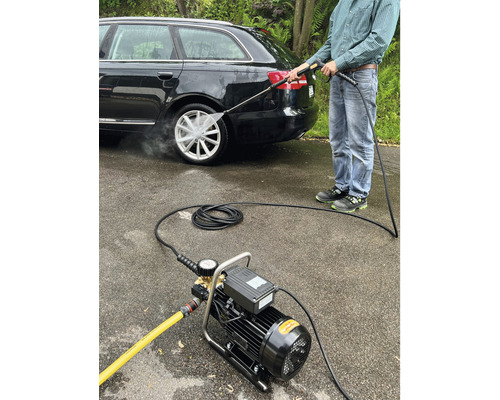 Ein Mann reinigt mit einem Hochdruckreiniger ein Auto.