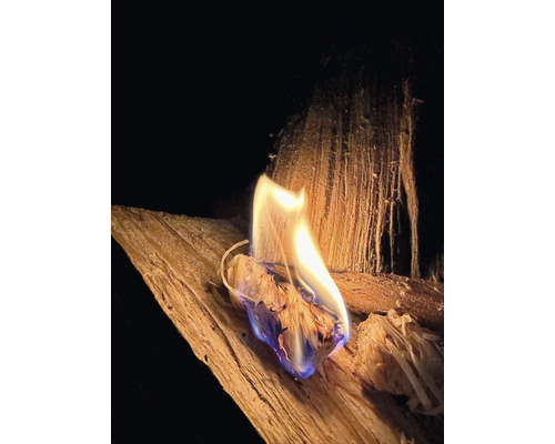 Ein brennender Anzünder aus Holz auf einem Holzscheit.