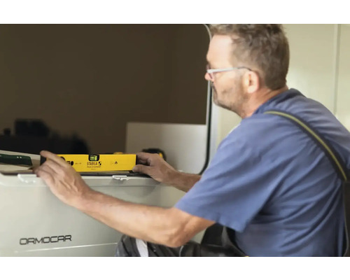 Ein Mann verwendet eine Wasserwaage, um eine Oberfläche auszurichten.