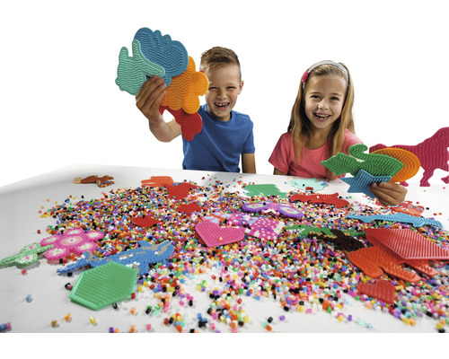 Kinder spielen mit Steckperlen und Stiftplatten am Tisch