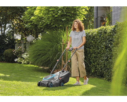 Frau bedient Rasenmäher im Garten.