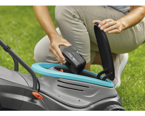 Frau setzt Akku in Rasenmäher ein