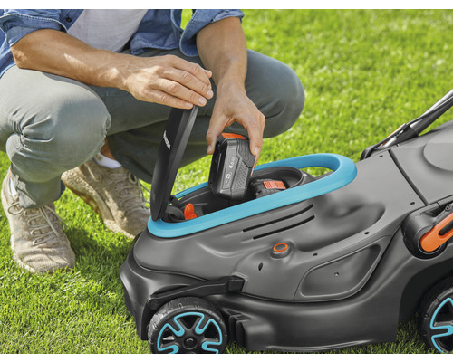 Eine Person legt einen Akku in einen Rasenmäher.