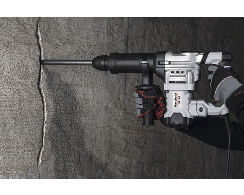 Eine Hand bedient einen Abbruchhammer Pattfield PA 1300 an einer Betonwand.