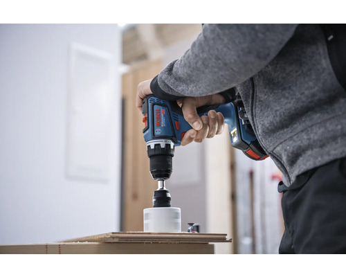 Eine Person bohrt mit einem Akku-Bohrschrauber ein Loch in ein Holzbrett.