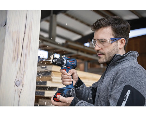 Mann bohrt mit Akku-Bohrschrauber in ein Holzstück