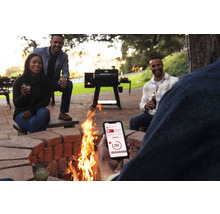 Szene im Freien mit einem Grill, einem Lagerfeuer und Menschen, die sich mit einem Mobiltelefon verbinden.