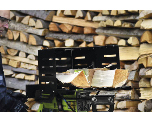 Holzspalter mit Holzscheiten vor einem Stapel Holz