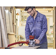 Ein Mann in einer Werkstatt benutzt eine Oberfräse für Holzarbeiten.