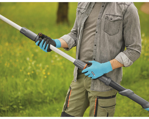 Eine Person mit Gartenhandschuhen hält eine Teleskopstielverlängerung im Freien.