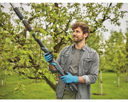 Mann benutzt eine Gardena Akku-Astschere zum Beschneiden von Ästen im Garten.