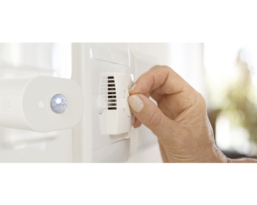 Eine Hand bedient einen Thermostat zur Temperaturregelung.