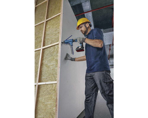 Ein Handwerker befestigt eine Gipskartonplatte mit einem Magazinschrauber an einer Wand.