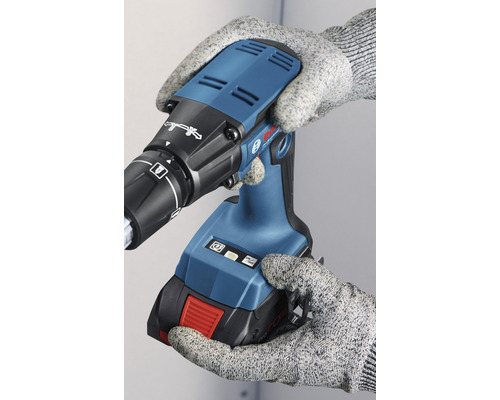 Akkuschrauber in der Hand mit Arbeitshandschuhen