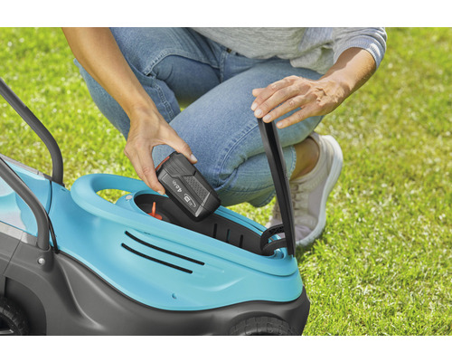 Frau setzt Batterie in einen Rasenmäher