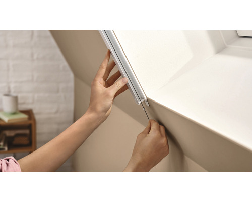 Person montiert ein Dachfensterrollo