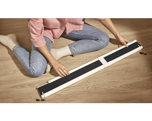 Frau sitzt auf dem Boden und montiert ein Rollo