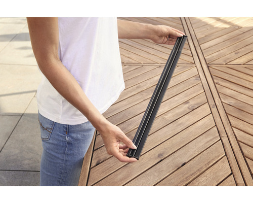 Eine Person hält eine Terrassendiele aus Verbundmaterial in den Händen.