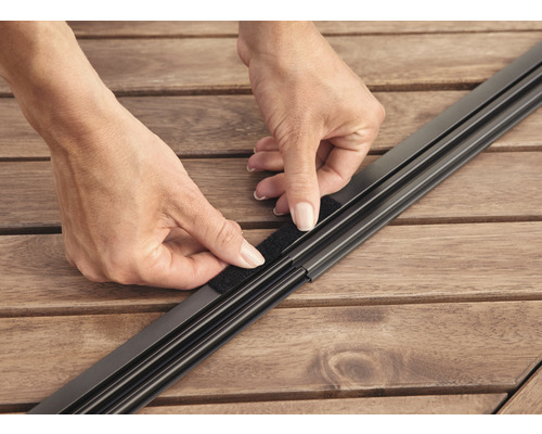 Person befestigt Klettverschluss an einem Insektenschutzgitter