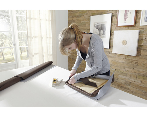 Frau polstert Stuhl mit Tacker, Stoff und Leder
