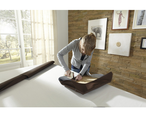 Frau polstert Möbel mit einem Tacker und Stoff