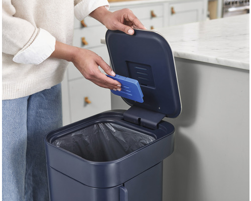 Eine Person wechselt den Geruchsfilter eines Abfalleimers.