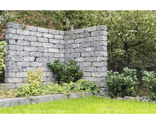 Graue Gartenmauer mit Bepflanzung im Garten