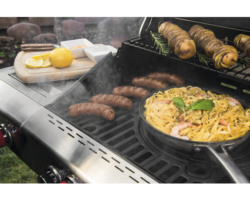 Grill mit Wurst, Pasta, Kartoffeln und Zitrone auf einem Schneidebrett