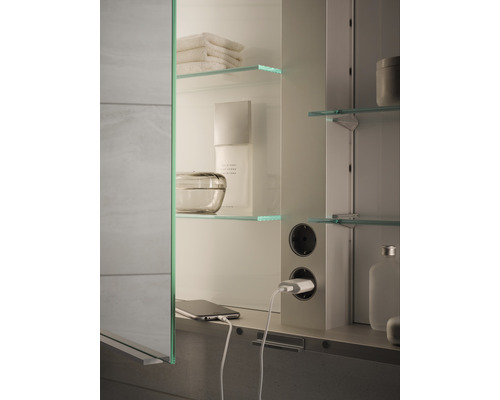 Badezimmerszene mit Spiegelschrank, Steckdosen, Glasablagen und diversen Badutensilien