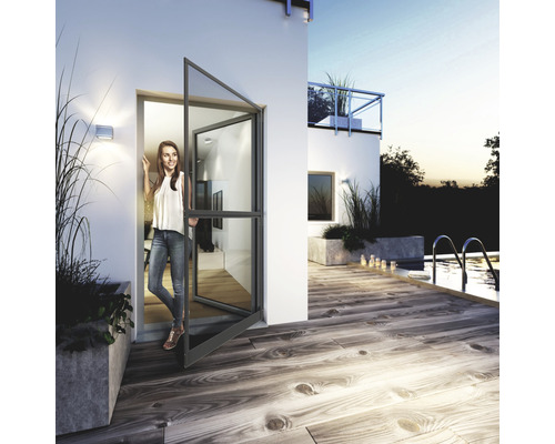 Außenansicht eines Hauses mit einer Frau, die in einer grauen Glastür steht, mit Terrasse und Pool