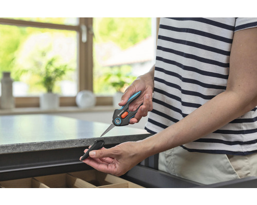 Person hält eine Gardena Pflanzenschere mit Schutzkappe über einer Schublade.