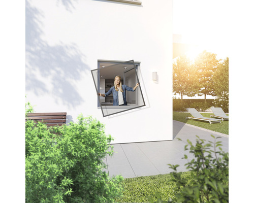 Frau montiert Insektenschutzgitter in einem Fenster im Freien.