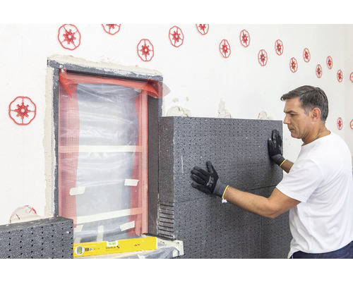 Mann montiert Wärmedämmung an einer Wand