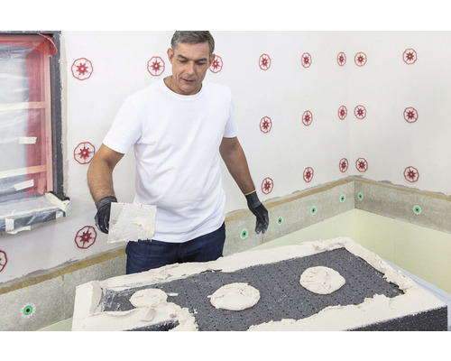 Mann trägt Klebemörtel auf eine Dämmplatte im Innenbereich auf