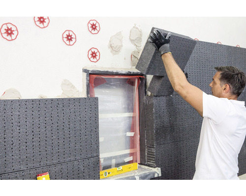 Mann bringt Wärmedämmung an einer Hauswand an