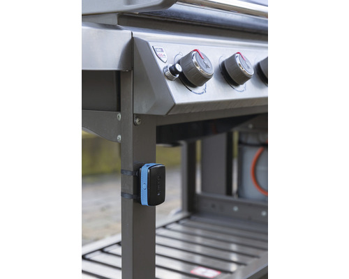 Detailansicht eines Gasgrills mit Reglern und einem Temperaturmessgerät am Rahmen.