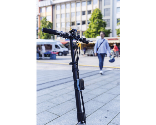 Lenker und Lenkstange eines Elektrorollers vor belebter Stadtkulisse