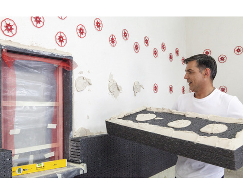 Handwerker bringt Dämmplatten an einer Hauswand an