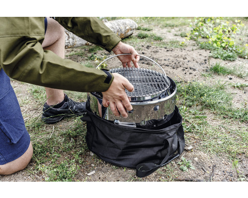 Person baut tragbaren Grill im Freien zusammen