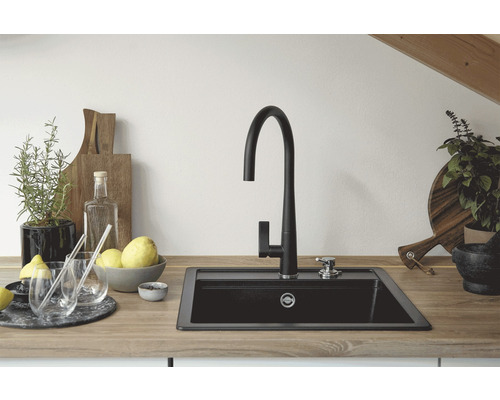 Küchenszene mit Spüle, Wasserhahn und dekorativen Elementen auf einer Arbeitsplatte.