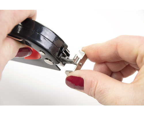 Person befestigt mit einer Zange eine Feder an einer Metallschiene.