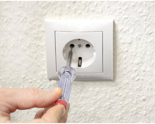 Eine Steckdose wird mit einem Phasenprüfer überprüft.