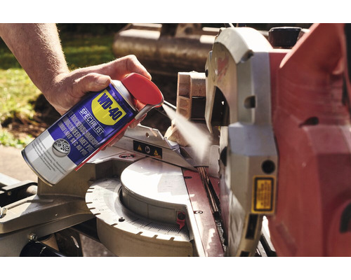 Eine Person sprüht ein WD-40 Spezialschmiermittel auf eine Säge.