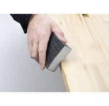 Eine Person schleift Holz mit einem Schleifklotz.