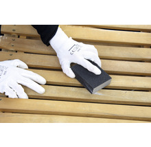 Eine Person schleift eine Holzoberfläche mit einem Schleifklotz und trägt dabei Handschuhe.