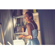 Frau mit Gießkanne vor einem Regal