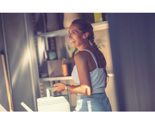 Frau mit Gießkanne vor einem Regal