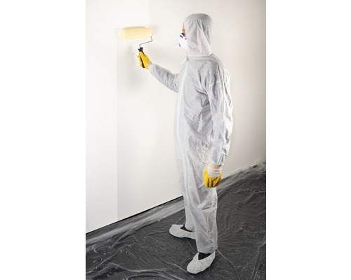 Person in Schutzkleidung streicht eine Wand mit einer Farbwalze.