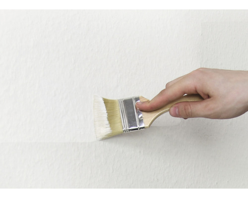 Eine Person streicht eine Wand mit einem Pinsel.